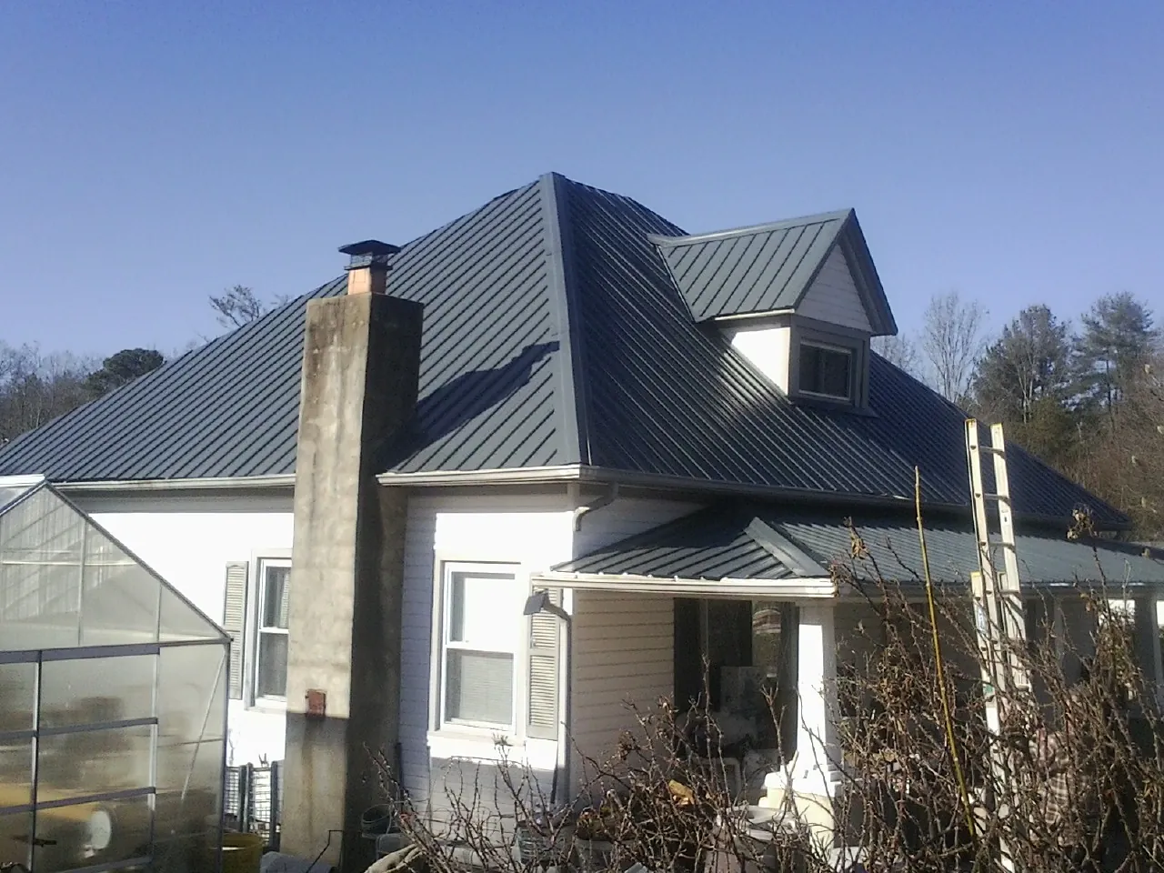 Dark blue standing seam metal roof on a white farmhouse with dormer — Slate & Tile Roof Repair by Roofing Brothers in Old Hickory