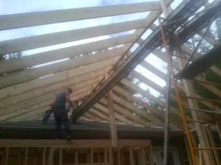 Rafters going up over a new addition with a worker on the wall in Old Hickory