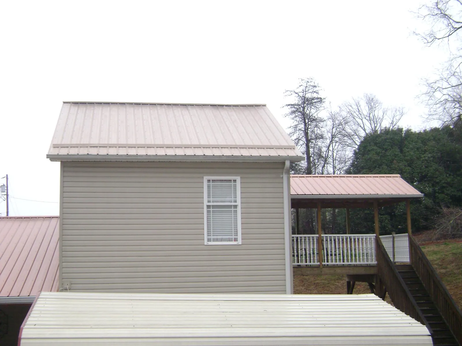 Tan metal roofs on a two story addition and attached porch, from a Roof Replacement job in Old Hickory